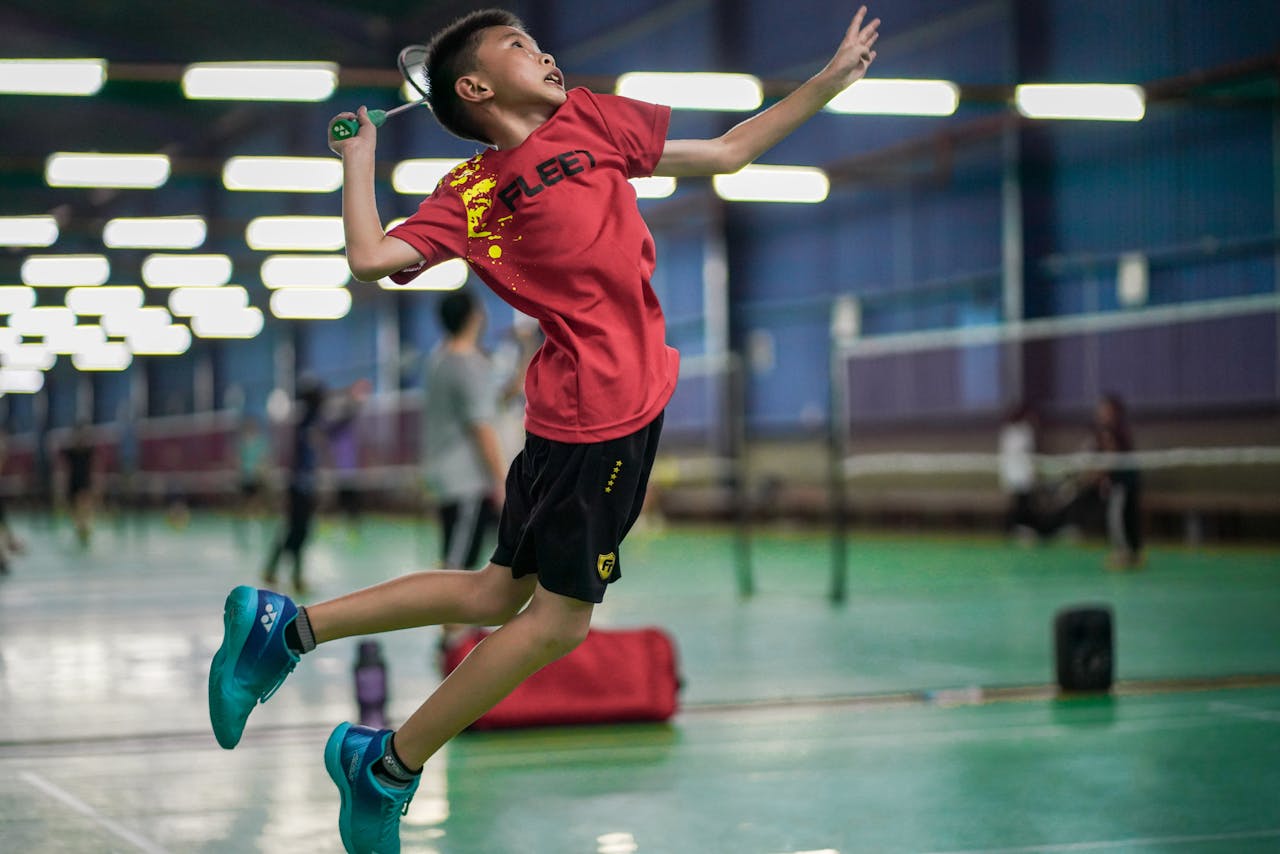 Boy Playing Badminton in Sports Hall